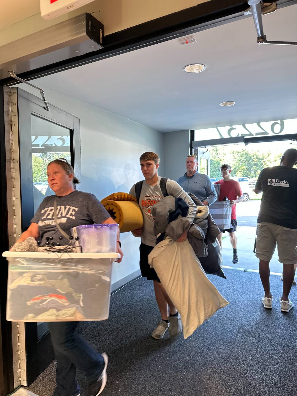 parents and students carrying student belongings as they move into student housing