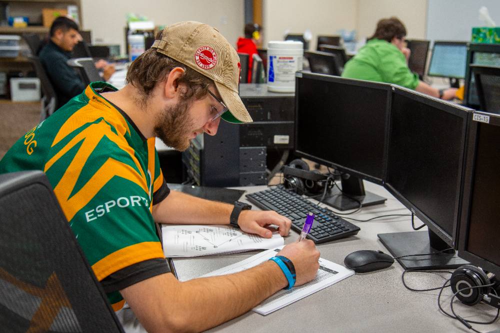 student sitting in the classroom in front of computer monitors