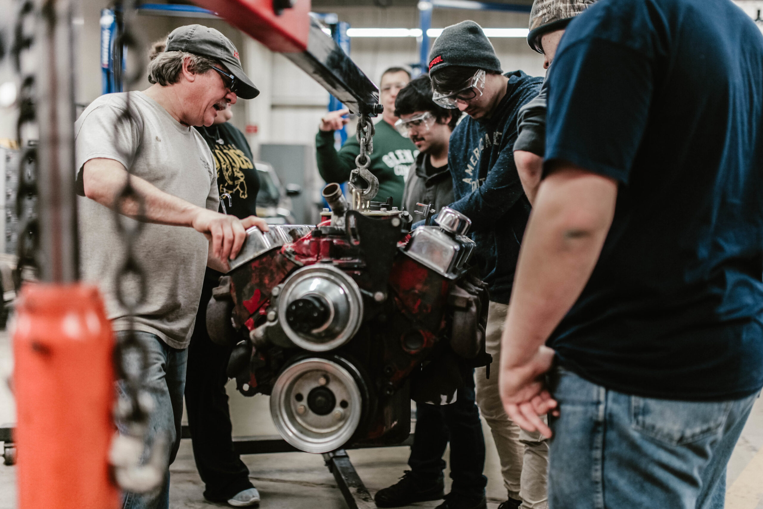instructor and students working on car engine
