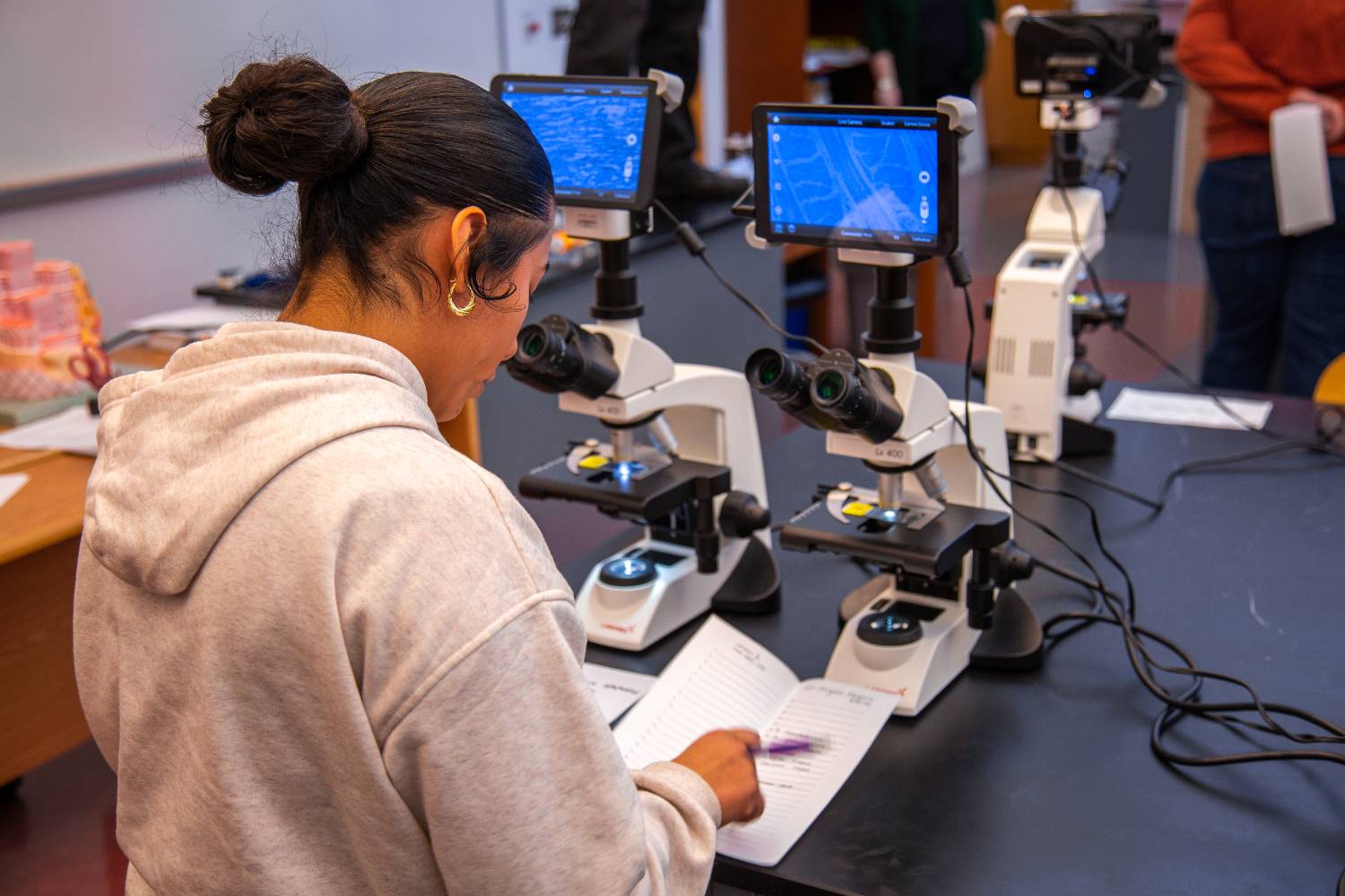 female student standing in front of a microscope