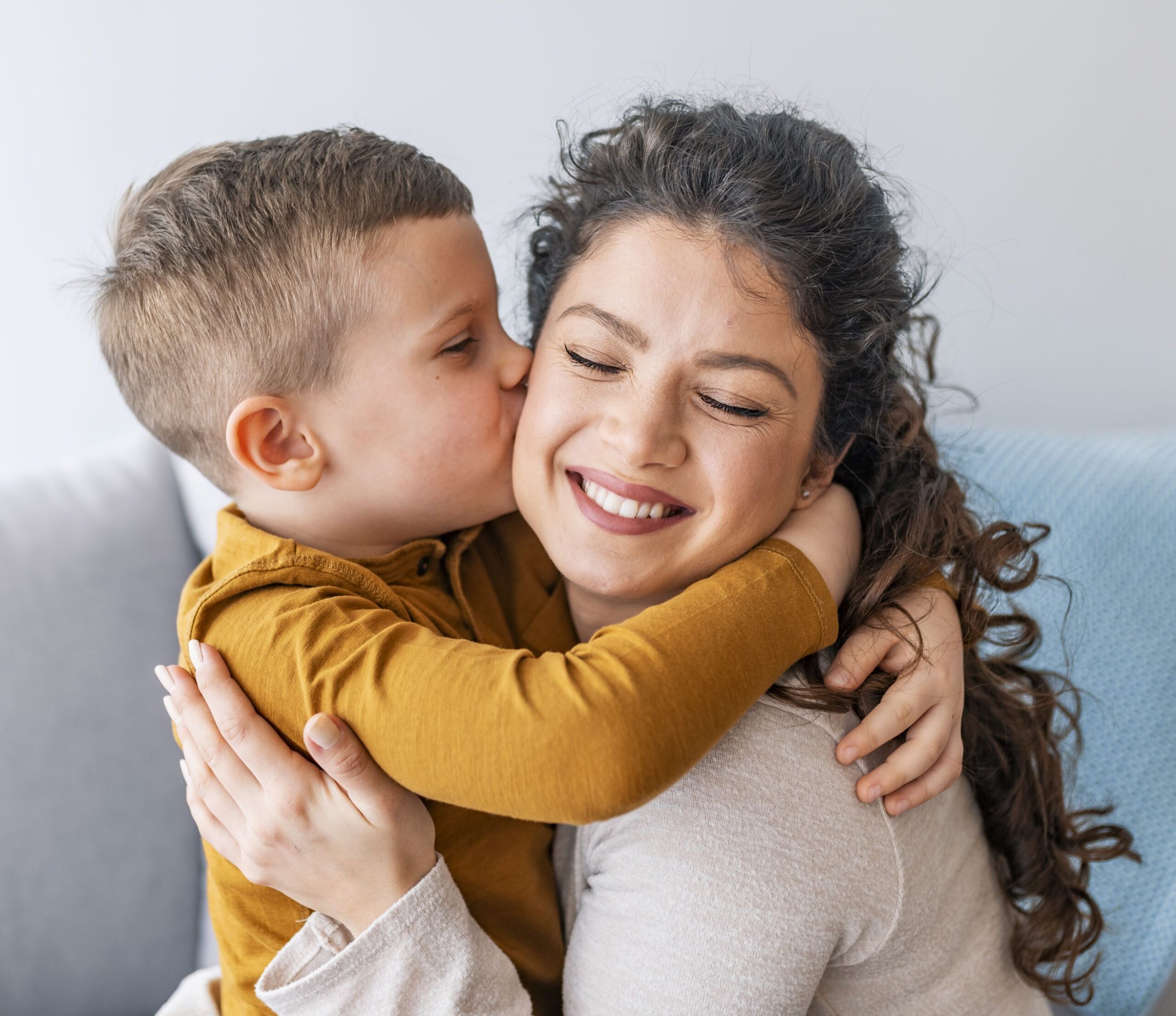 small boy kissing a woman on the cheek as he hugs her