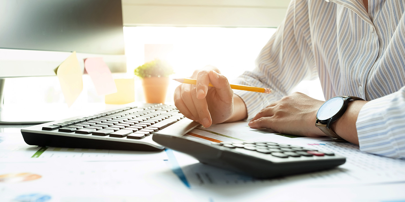 Man sitting at a table with a pencil in his hand in front of a keyboard and a calculator