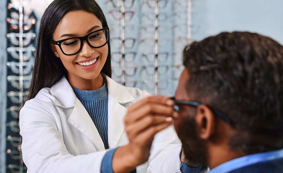 Female optician fitting glasses on a person in an optician store