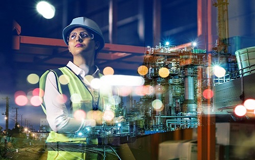 women standing on an industrial site, wearing a safety hat and yellow vest