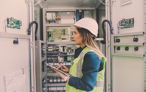 female wearing safety vest and hard hat in an electrical room