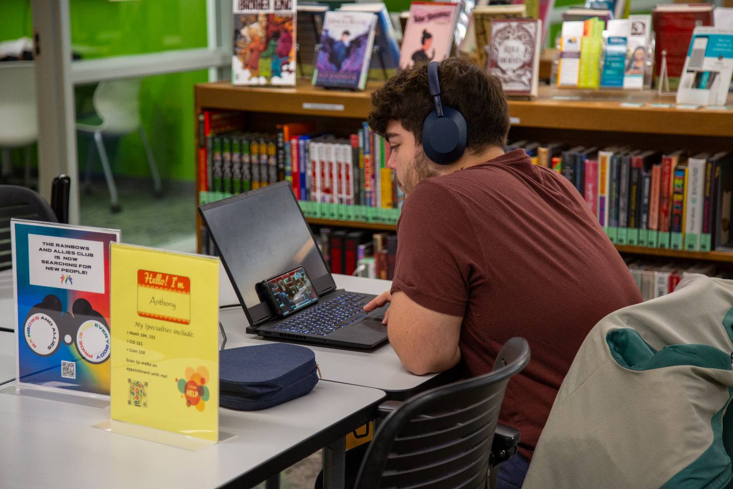 male student sitting in library using laptop