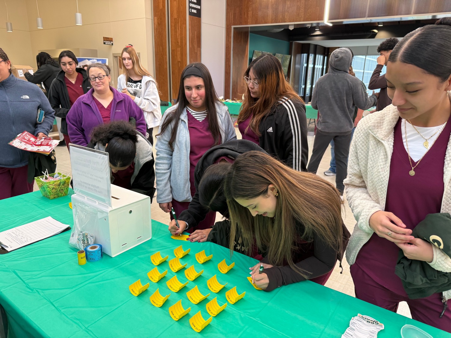 first generation Allied helps students at a first-generation celebration event, filling out slips to enter a contest.